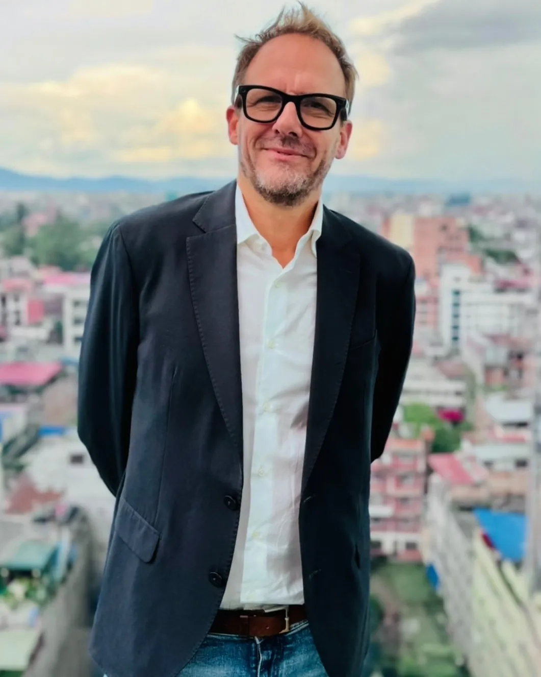 Frédéric Kauffmann de pie, con camisa blanca y chaqueta oscura, ante una vista panorámica de la ciudad